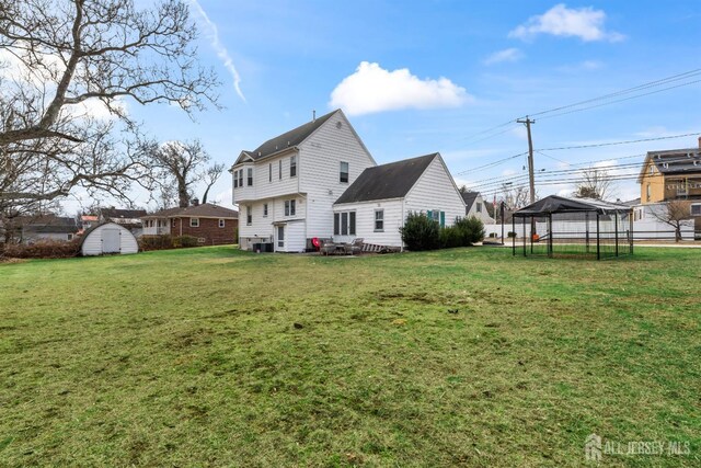 rear view of house featuring a storage unit and a lawn