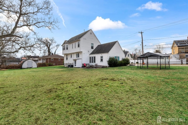 rear view of property with a lawn and a storage unit