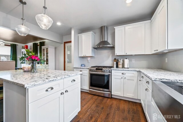 kitchen featuring white cabinets, stainless steel gas range, dark hardwood / wood-style flooring, wall chimney range hood, and pendant lighting