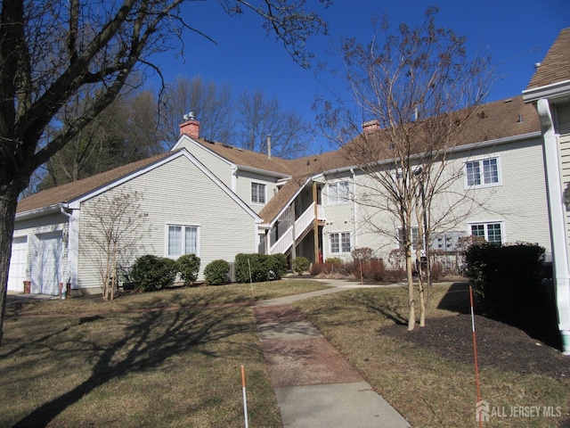 view of front of home featuring a garage, a chimney, and a front yard