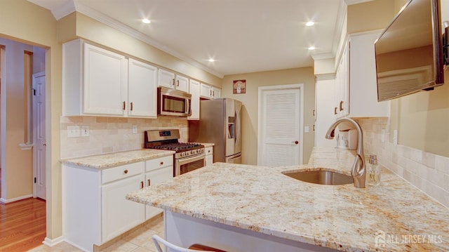 kitchen featuring tasteful backsplash, white cabinetry, sink, stainless steel appliances, and light stone countertops