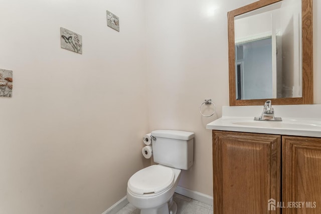 bathroom with toilet, baseboards, vanity, and tile patterned floors