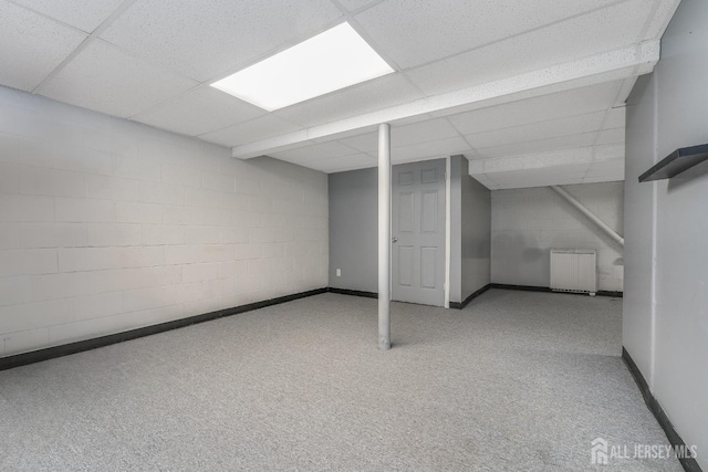 finished below grade area with radiator heating unit, carpet, concrete block wall, and baseboards