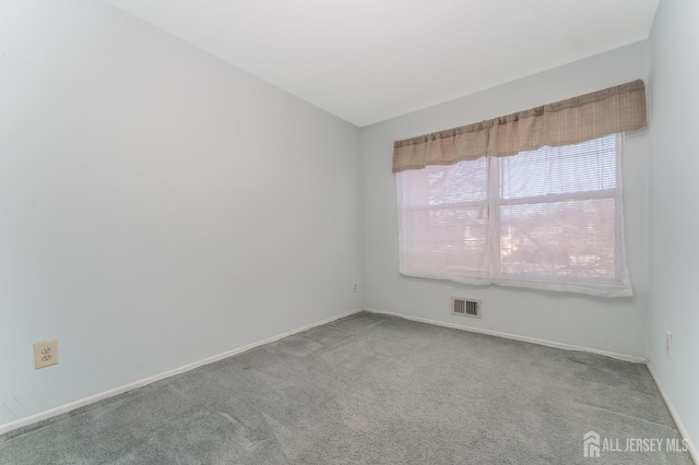 carpeted spare room featuring visible vents and baseboards