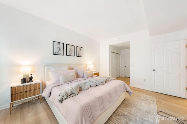 bedroom featuring light wood-style flooring, baseboards, and a closet