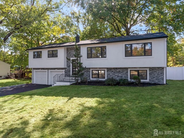 raised ranch featuring a front yard and a garage