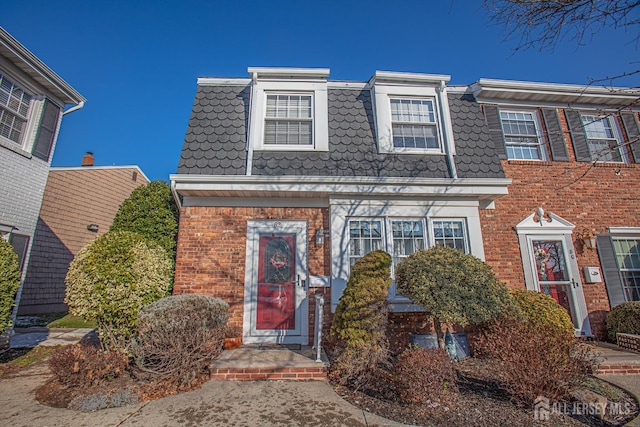 view of front of home with mansard roof and brick siding