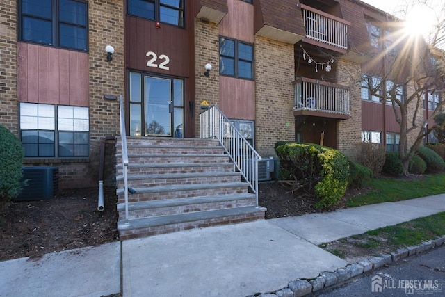 view of exterior entry featuring central air condition unit and brick siding