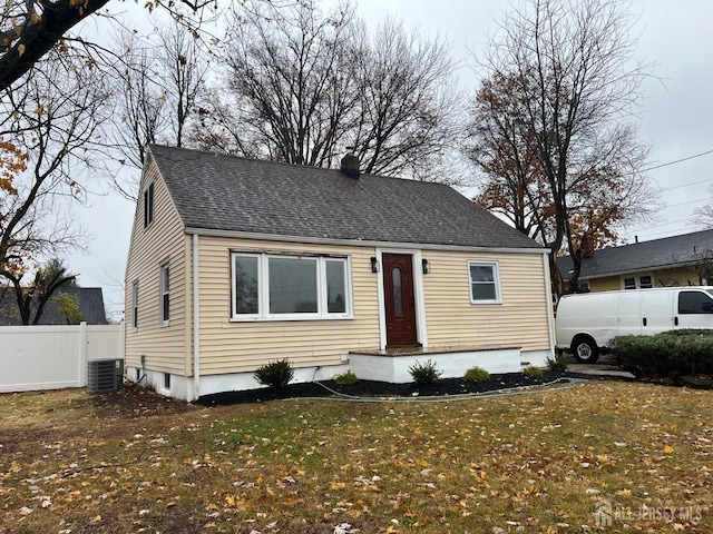 bungalow featuring central air condition unit, fence, a front lawn, and roof with shingles