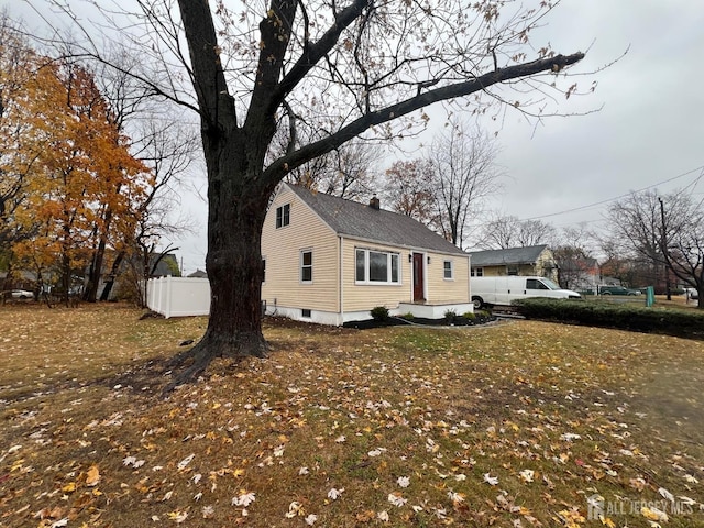 view of side of home featuring a chimney and fence