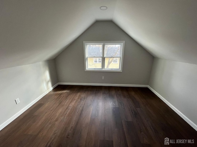 bonus room featuring baseboards, vaulted ceiling, and dark wood-type flooring