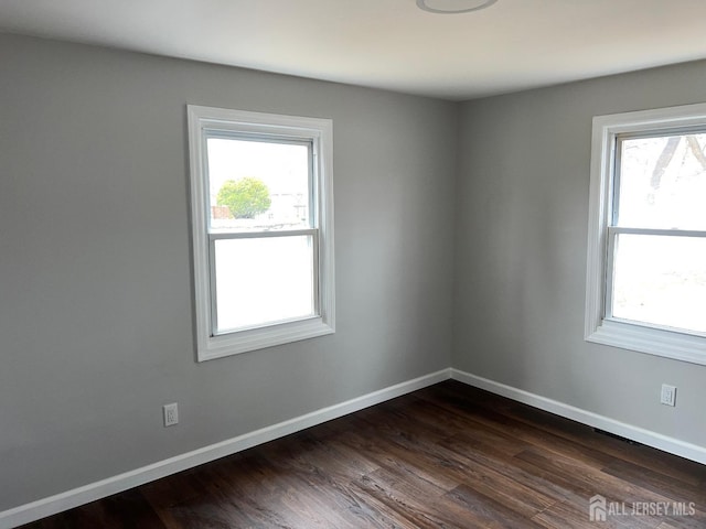 empty room with dark wood-style floors and baseboards