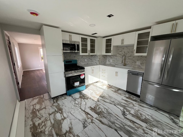 kitchen with marble finish floor, light countertops, decorative backsplash, appliances with stainless steel finishes, and a sink