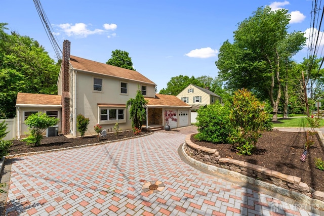 299 Riva Ave, East Brunswick, NJ 08850 - view of front of home featuring stucco siding, an attached garage, decorative driveway, a chimney, and central air condition unit