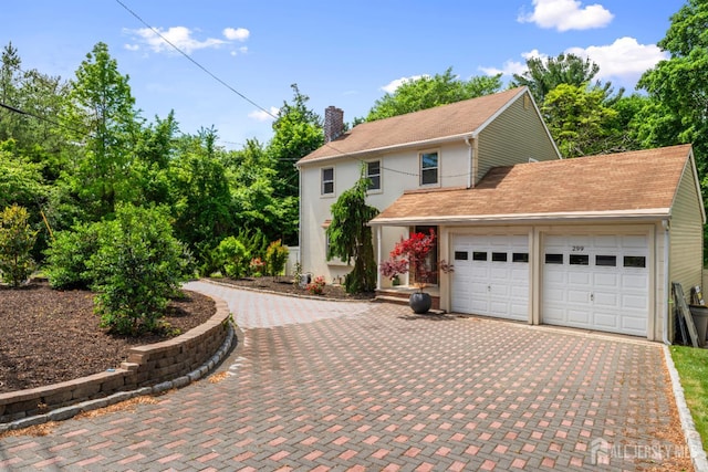 299 Riva Ave, East Brunswick, NJ 08850 - view of property exterior featuring decorative driveway, a chimney, an attached garage, stucco siding, and a shingled roof