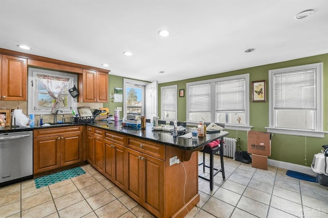 kitchen featuring sink, a breakfast bar area, radiator, kitchen peninsula, and dishwasher