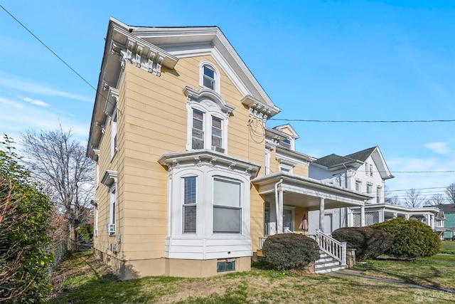 view of side of property featuring covered porch and a lawn