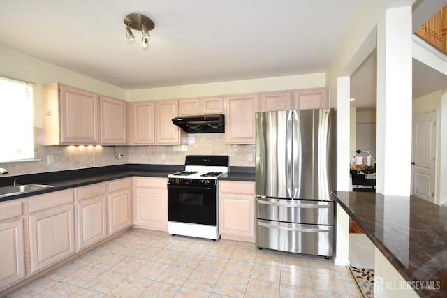 kitchen with stainless steel refrigerator, white gas stove, light brown cabinets, and sink