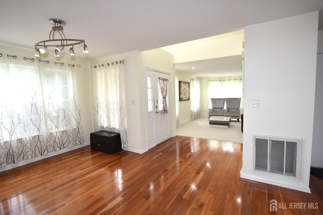 entrance foyer with a wealth of natural light, an inviting chandelier, and hardwood / wood-style flooring