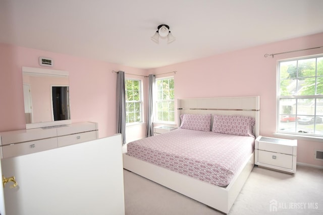 bedroom with light carpet and multiple windows