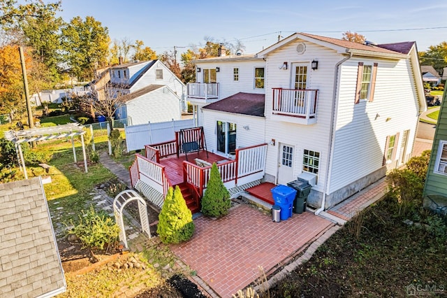rear view of house featuring roof with shingles, a patio area, fence, a gate, and a balcony