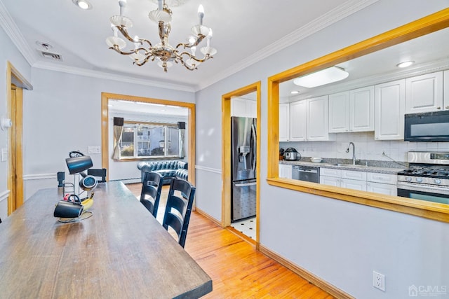 kitchen with tasteful backsplash, a notable chandelier, white cabinetry, appliances with stainless steel finishes, and a sink