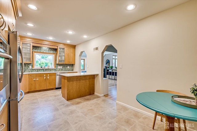207 Dellwood Rd, Metuchen, NJ 08840 - kitchen with appliances with stainless steel finishes, arched walkways, a peninsula, tasteful backsplash, and light countertops