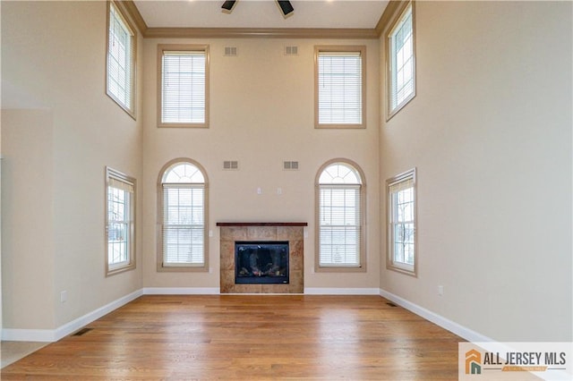 4 Kristina Ct, East Brunswick, NJ 08816 - unfurnished living room with healthy amount of natural light, a tiled fireplace, wood finished floors, a high ceiling, and ornamental molding