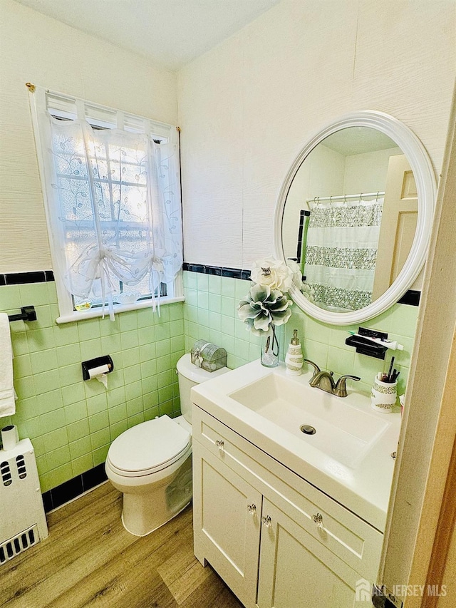 bathroom with toilet, a wainscoted wall, wood finished floors, vanity, and radiator heating unit