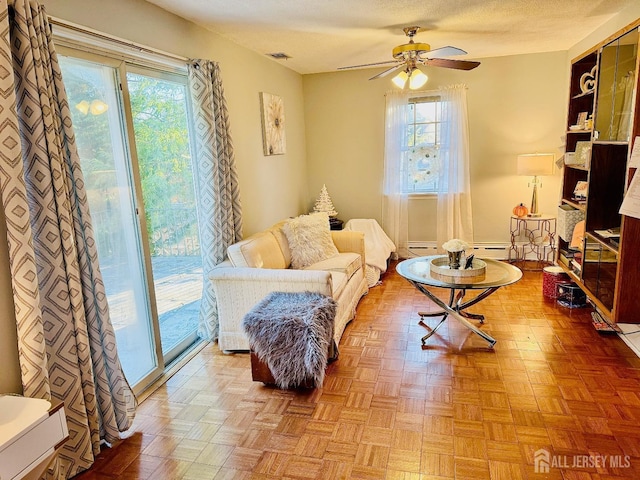 living area featuring a ceiling fan, visible vents, and a textured ceiling