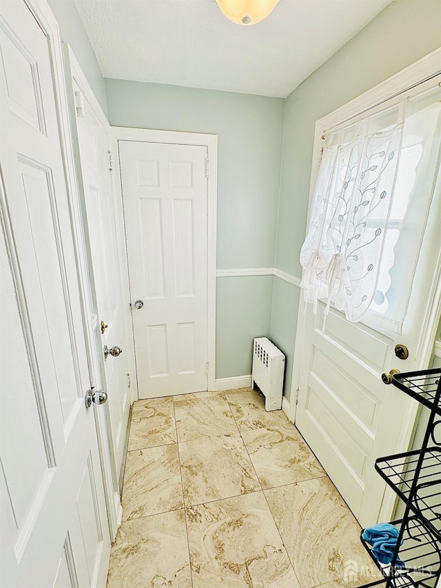 doorway featuring radiator, a textured ceiling, and baseboards