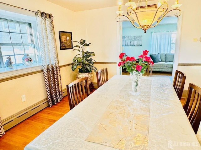 dining area with baseboard heating, wood finished floors, and a notable chandelier