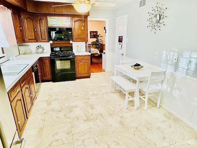 kitchen featuring visible vents, a ceiling fan, light countertops, black appliances, and a sink