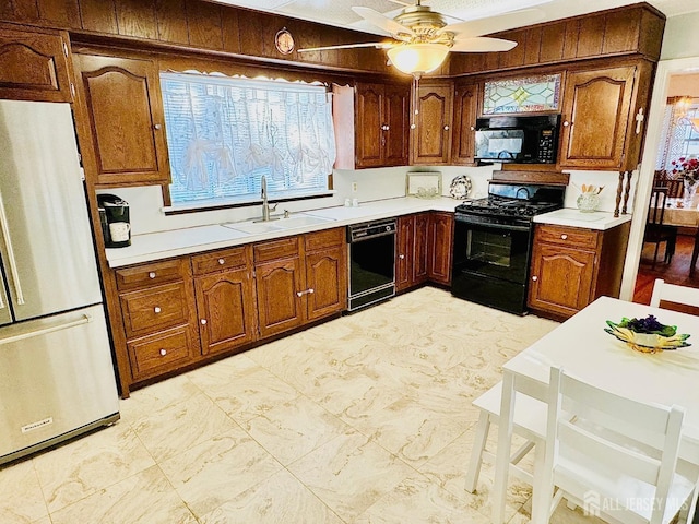 kitchen featuring black appliances, brown cabinetry, a sink, and light countertops