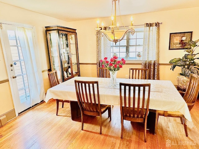 dining area with light wood-type flooring and an inviting chandelier