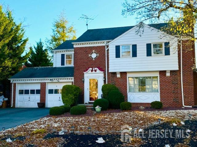 view of front facade with an attached garage, aphalt driveway, and brick siding