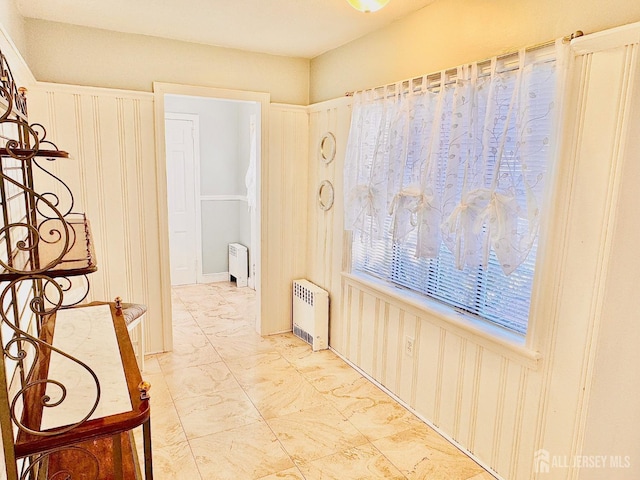 hallway with marble finish floor and radiator heating unit