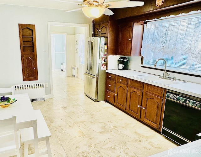 kitchen with dishwasher, radiator heating unit, freestanding refrigerator, light countertops, and a sink