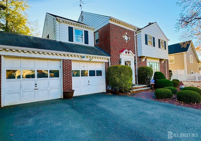 view of front of property with a garage, brick siding, driveway, and fence