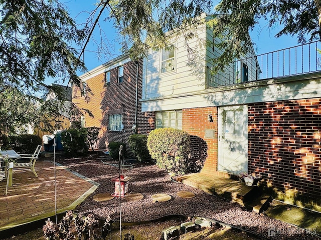 rear view of house with a patio area and brick siding