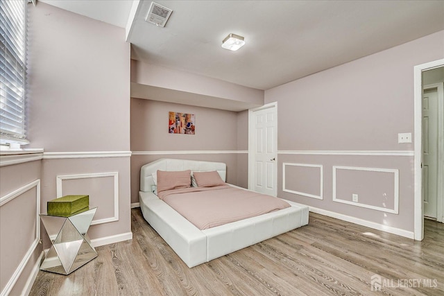 bedroom with baseboards, wood finished floors, and visible vents