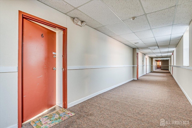 hallway with baseboards, carpet, and a drop ceiling