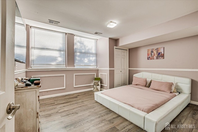 bedroom featuring wood finished floors, visible vents, and baseboards
