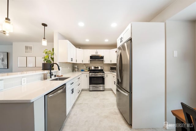 kitchen with a sink, visible vents, appliances with stainless steel finishes, backsplash, and decorative light fixtures