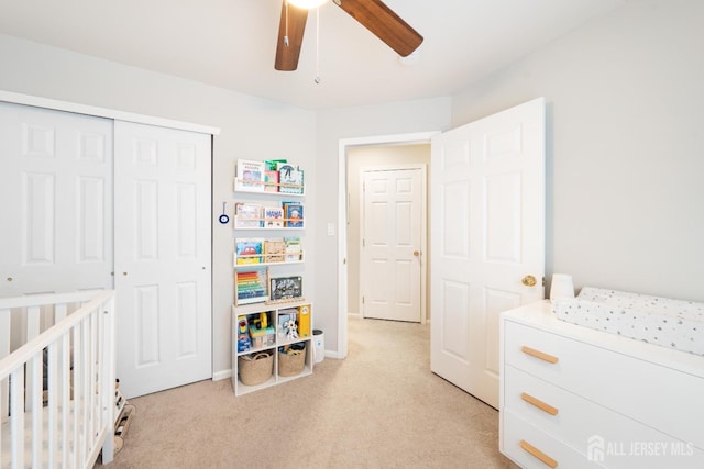 bedroom featuring ceiling fan, a closet, baseboards, and light colored carpet