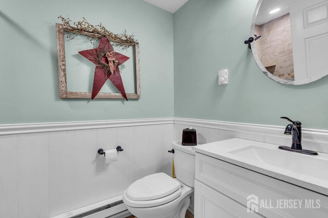 bathroom featuring a wainscoted wall, toilet, vanity, and a baseboard radiator