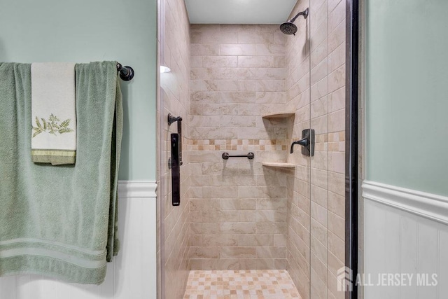 full bathroom with a shower stall and a wainscoted wall
