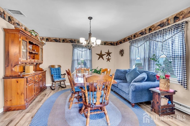 dining area featuring a chandelier, light wood-style floors, baseboards, and baseboard heating