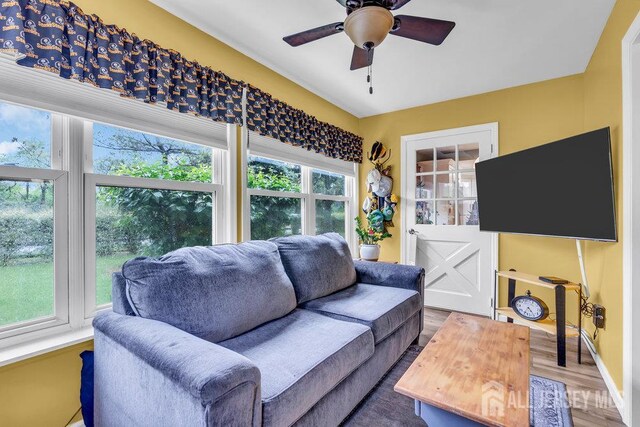 living room with a ceiling fan, wood finished floors, and baseboards