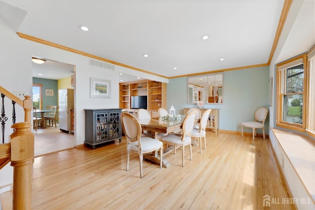 dining room with ornamental molding, healthy amount of natural light, wood finished floors, recessed lighting, and baseboards